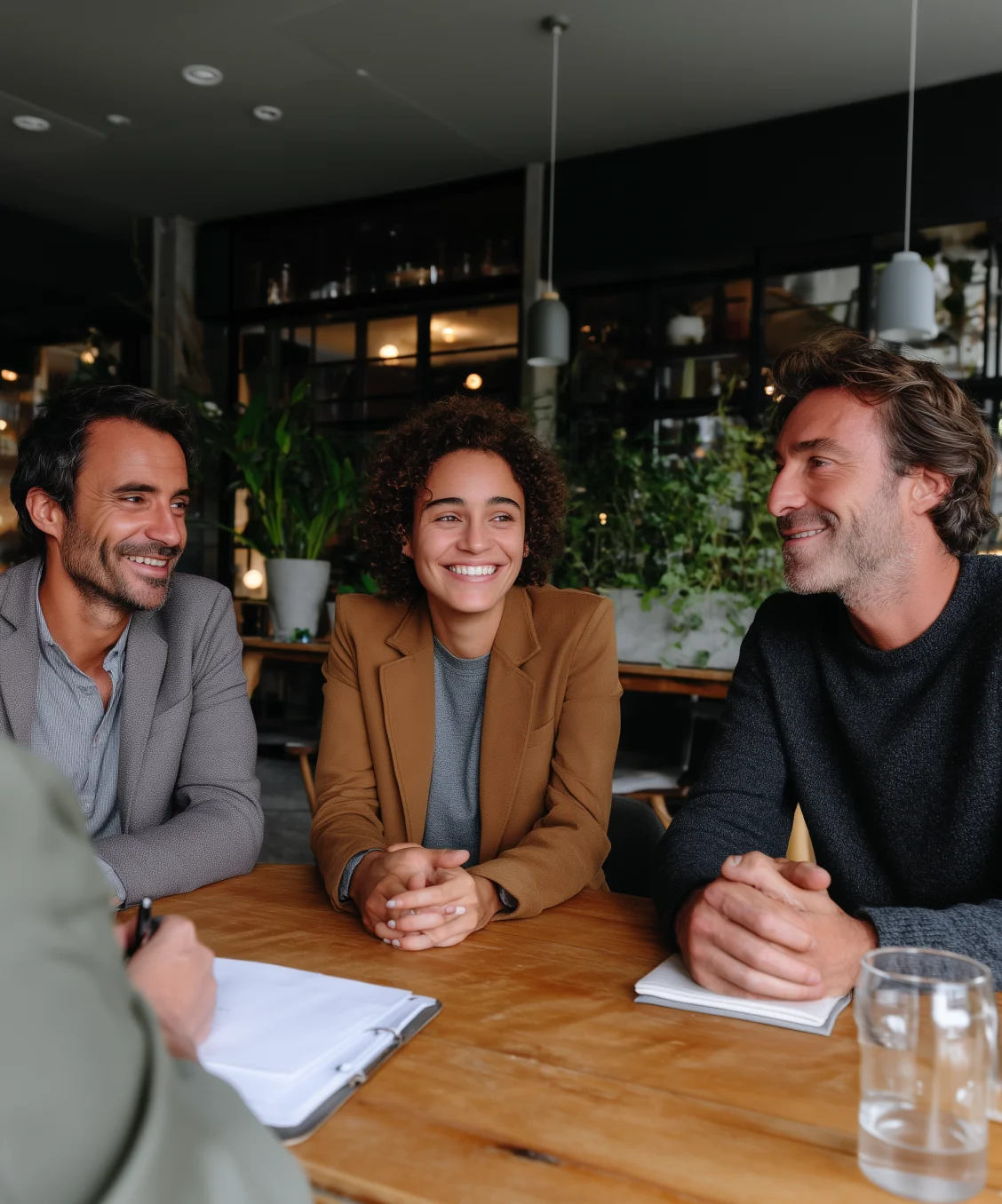 Three colleagues smiling around a meeting table, representing a trustworthy insurance team